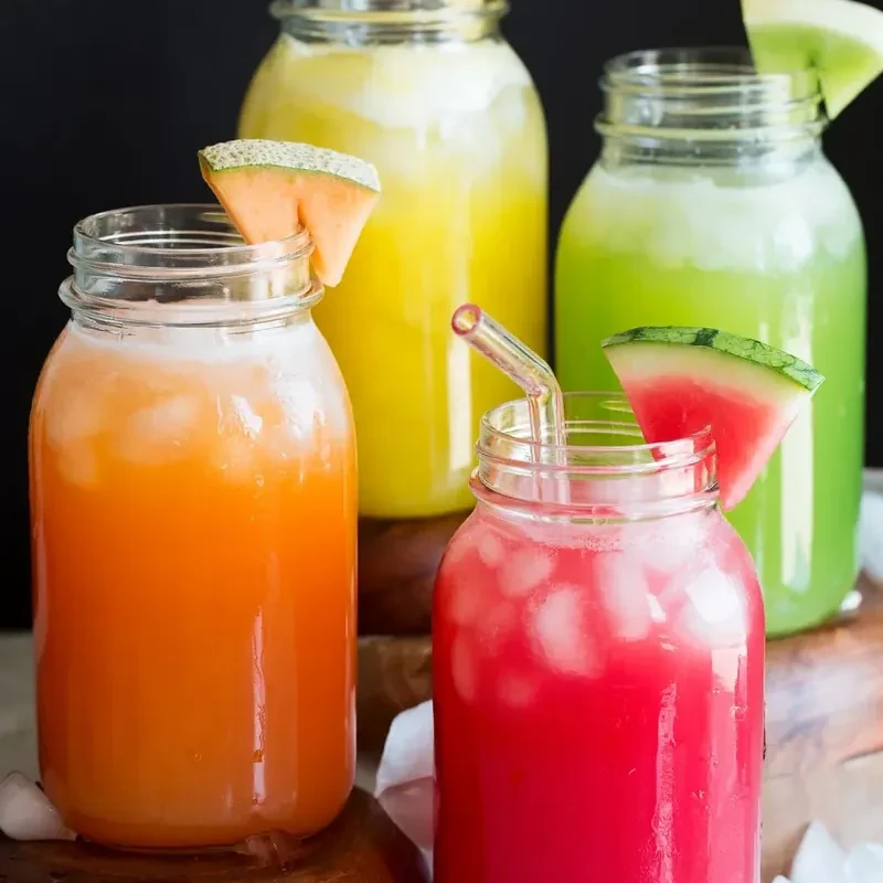 Jars of agua fresca in orange, yellow, green and red