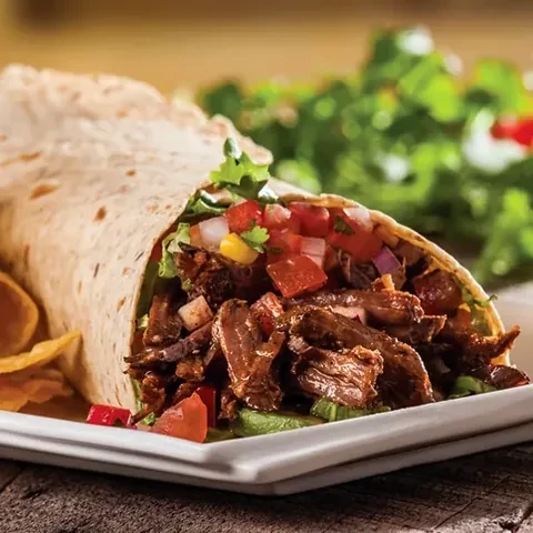A burrito cut open showing shredded barbacoa beef and pico de gallo