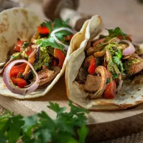Two veggie tacos with sautéed mushrooms, peppers and onion